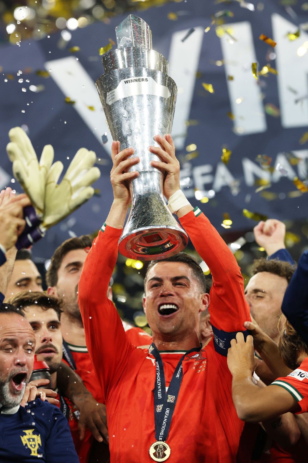 Person in red jersey holding a trophy with confetti and 'UEFA Nations League' logo in the background