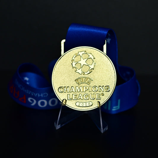2006 UEFA Champions League Medal Front View, Barcelona Champion Gold Alloy Medal with Official UCL Logo, 2006 Final Commemorative Medal on Clear Display Stand with Blue Tournament Ribbon