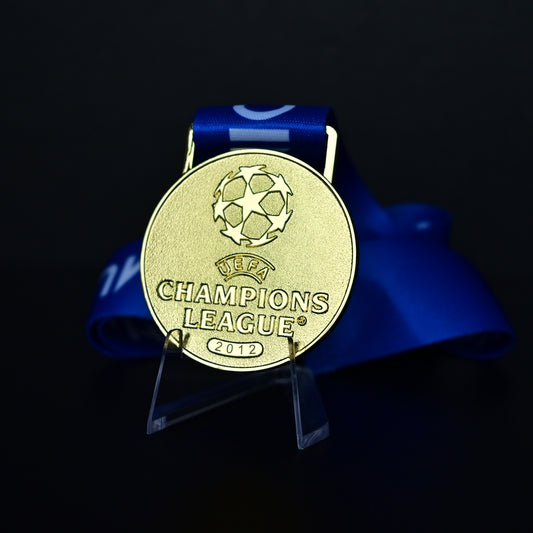 2012 UEFA Champions League Medal Front View, Chelsea Champion Gold Alloy Medal with Official UCL Logo, 2012 Final Commemorative Medal on Clear Display Stand with Blue Tournament Ribbon