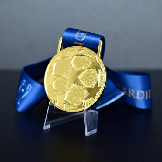 Gold medal with blue ribbon on a stand against a dark background