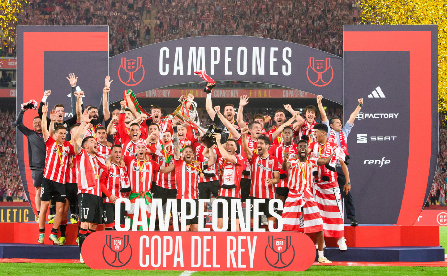 Football players celebrating with a 'Campeones' banner on a stadium field.