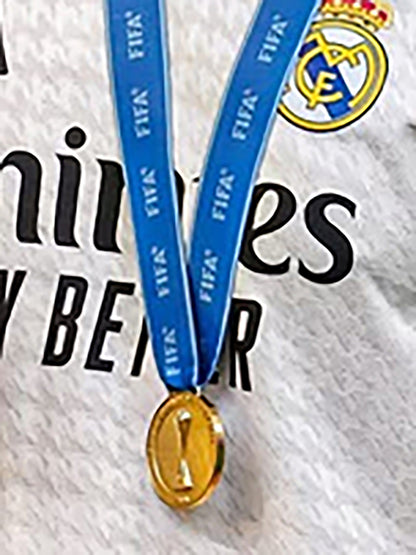 Medal with blue ribbon featuring FIFA and Real Madrid logos on a textured background.