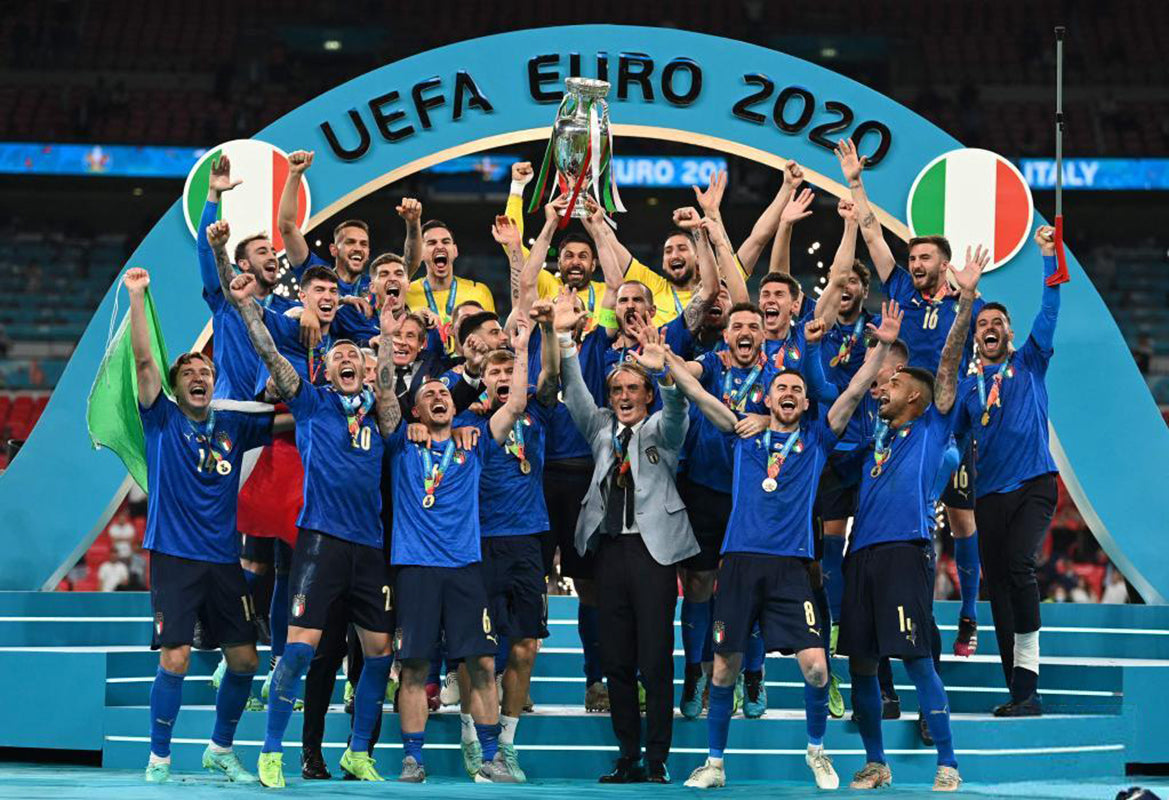 Italy national team lifting the Coupe Henri Delaunay trophy under UEFA Euro 2020 arch, celebrating their London Wembley final triumph. Historic championship moment for Italian football.
