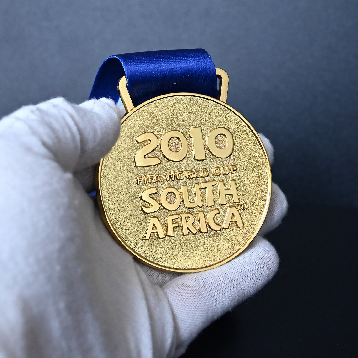 South Africa 2010 FIFA World Cup Spain Champions Medal - Front Close-Up Held in White Gloves, Highlighting Premium Alloy Finish & Official Design
