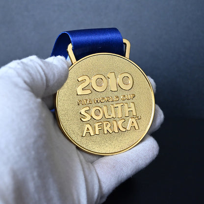 South Africa 2010 FIFA World Cup Spain Champions Medal - Front Close-Up Held in White Gloves, Highlighting Premium Alloy Finish & Official Design