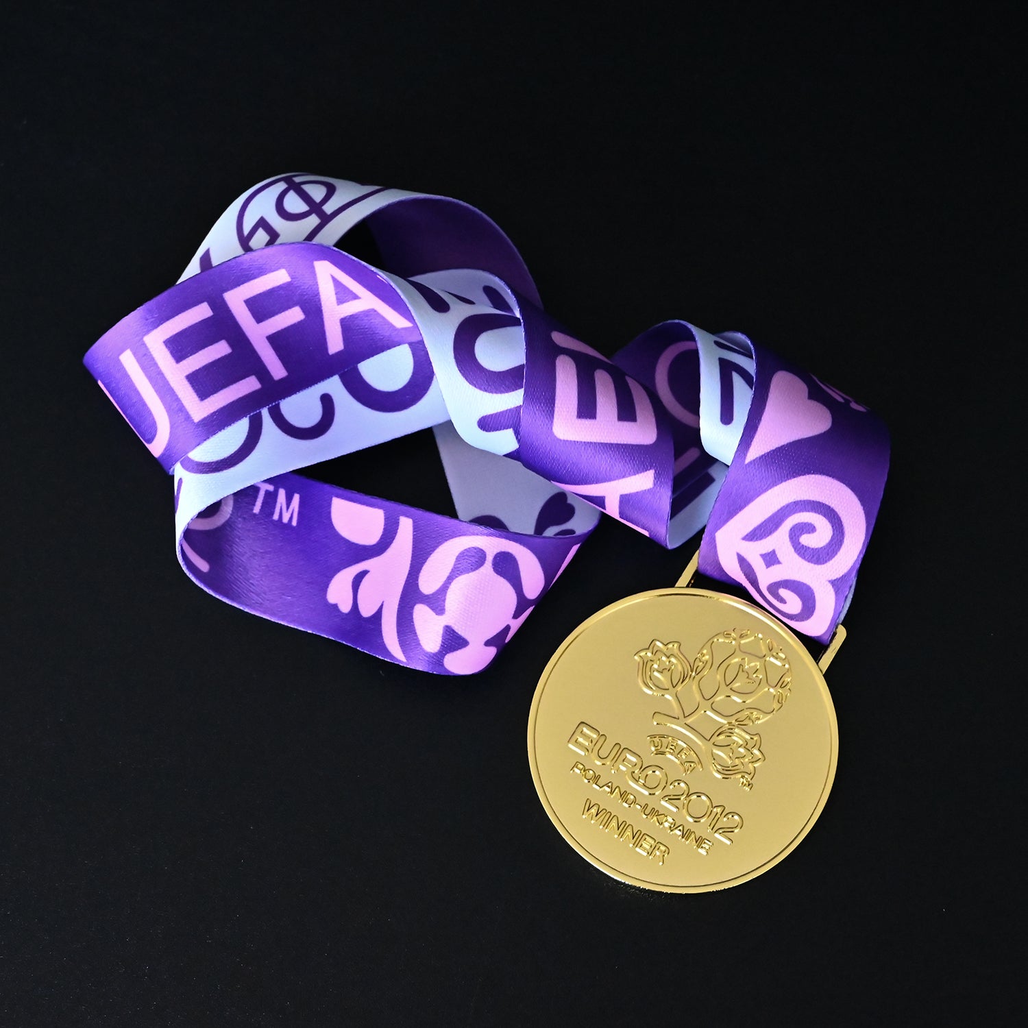 UEFA Euro 2012 medal, full purple tournament ribbon flat lay, front floral winner design, Poland-Ukraine, commemorative keepsake, football collectible
